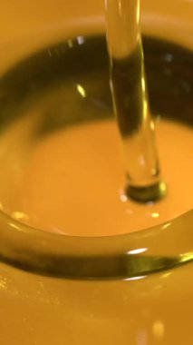 Zeytinyağının yavaş çekimde cam bir kaba dökülmesi. Kalın altın sıvı pürüzsüzce akar zarif yansımalar ve yumuşak gölgeler yaratır. Saniyede 1000 kare çekiliyor.