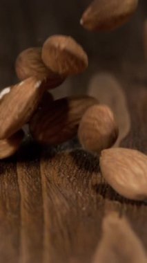 Hayalar yüksekten düşer ve tahta bir masaya çarpar. Darbe yüzeyden hafifçe sekmelerine neden oluyor. İzleyiciler ahşap ve fındıkların dokusunu görebilir..