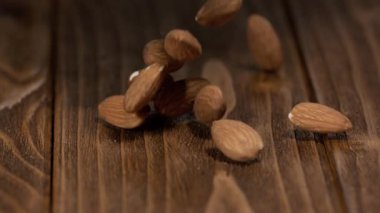 Bademler mutfaktaki ahşap bir masaya düşerken görülür. Pencereden gelen ışık mekanı aydınlatıyor. Bademlerin dokusuna ve masaya odaklanıyoruz..