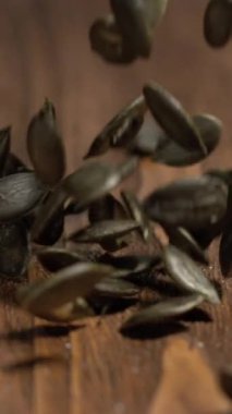 Küçük tohumlar ahşap bir yüzeye düşer ve hareketlerini yavaş çekimde gösterir. Işıklandırma tohumların ve ahşabın dokusunu vurguluyor. Eylem ayrıntılı olarak kaydedildi..