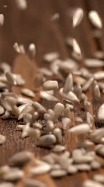 Tahta bir masaya düşen tohumlar, bir insan onları bahçelerine dikmeye hazırlanırken. Eylem yavaş ilerliyor, ekme işlemi sırasında tohumları vurguluyor.