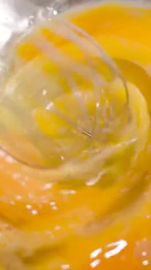 Yemek hazırlığı için açık bir kasede bir yumurta çırpılıyor. Sarı sarısı kırılır ve yumurta akıyla karışır. Mutfakta yemek pişirme etkinliği olduğunu gösteriyor..