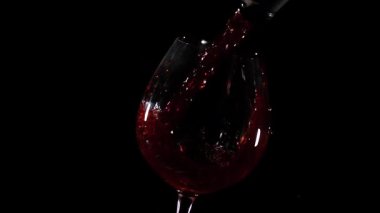 Kırmızı şarap kenarına kadar dolarken berrak bir bardağa doldurulur. Koyu arka plan şarabın zengin rengini vurguluyor. Bu an arkadaşlarla sosyal bir etkinlik sergiliyor..