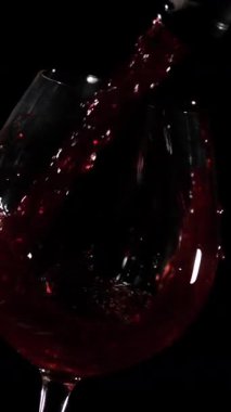 Kırmızı şarap koyu arkaplanı olan bir bardağa doldurulur. Şarabın sesi havayı dolduruyor. Dostlar birlikte vakit geçirmenin keyfini çıkarıyorlar..
