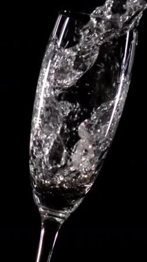 Siyah arka planda şeffaf bir şarap kadehine dökülen beyaz şarabın yakın görüntüsü. Sıvı sıçramalar ve kabarcıklar açıkça görülebiliyor çarpıcı bir kontrast ve zarif bir atmosfer yaratıyor. Konsept