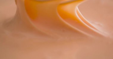 Bir insan çırpıcı kullanarak kremalı bir karışımı kaseye karıştırıyor. Mutfak aydınlık ve tezgah temiz. Malzemeleri hazırlarken sabah oluyor..