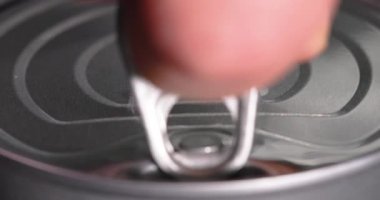Ton balığı konservesini açan bir elin yakın görüntüsü. Çekme sekmesi metal kapağı kaldırır ve paketlenmiş gıdaya erişim sürecini başlatır. Görüntüler konserve yemek hazırlığını temsil ediyor