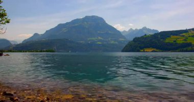 Kayalık bir sahildeki ayak izleri dağları yansıtan berrak bir göle götürür. İnsanlar doğanın tadını çıkarıyorlar güneş suyun ve yakınlardaki manzaranın üzerine doğarken..