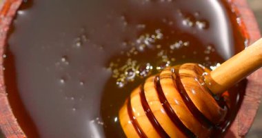 Yakın çekim kasede kalın bal olduğunu gösteriyor. Balın içinde kullanıma hazır ahşap bir kepçe oturuyor. Bu an balın dokusunu ve rengini yakalar..