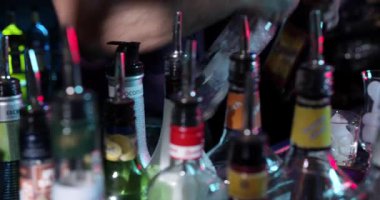 Barmenler çeşitli içkileri karıştırırken müşteriler sohbet ediyor ve barda vakit geçiriyorlar. Parlak ışıklar gece hayatı sahnesinde canlı bir atmosfer yaratır..