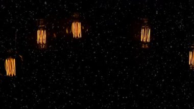 Ampullerden gelen sıcak ışık karanlık bir uzayda parlar ve rahat bir atmosfer yaratır. Ampuller gece boyunca yavaşça asılır ve etrafı aydınlatır..