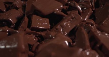 Çikolata parçaları bir fabrikada erir. Süreç şekil değiştirdikçe pürüzsüz ve zengin dokuları gösteriyor. Çevre şeker üretimine odaklı.