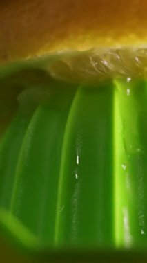 Taze limonun elle sıkıldığını ve meyve suyunun aktığını yakın çekimde görebilirsiniz. Makro çekim turunçgil dokusunun canlı yeşil ve sarı tonlarını ve doğal tazeliğini gösteriyor. Sağlıklı içecek kavramı