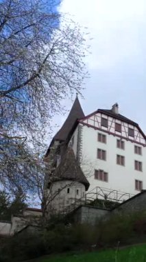 Ağaçlar ve çimlerle çevrili eski bir kaleyi ziyaret etmek. Gökyüzünde bazı bulutlar var ve kale eşsiz bir tasarıma sahip. Doğa bu yere güzellik katar..