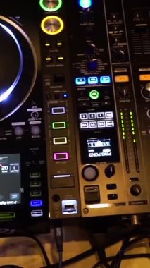 Yakın çekim DJ Karıştırıcı Kontrolleri ve Eller Faders ve Knobs, LED Ölçer Nabız, Güverte ve Kablolar Görünür,