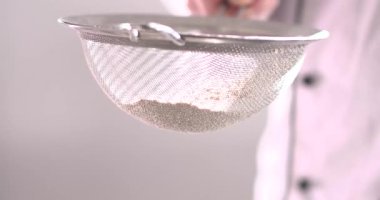 Bir insan ince bir ağ süzgecini bir kasenin üzerine koyup, içine un döker. Un, ellerken nazikçe düşer ve pişirme görevine hazırlanır. Mutfak düzeni basit ve işlevsel..