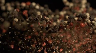 super slow motion closeup airborne peppercorns in motion, dark background, warm rim lighting, red black white