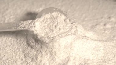 Süper yavaş çekim kreatin tozu tepeciklerin üzerine düşüyor plastik kepçenin makro görüntüsü