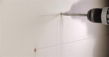 Bir rafı desteklemek için duvarı delme işlemi. Matkap ucu duvarı delip geçiyor ve kurulum için temiz delikler açıyor..