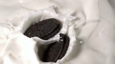 Süper yavaş çekim geniş kurabiye çifti süte dalıyor, dinamik sıçrama koreografisi yavaş çekimde, süt tacında