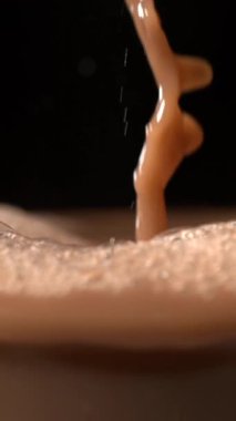 Süper yavaş çekimde çikolata sıçraması ve hava damlacıkları siyah arka plana karşı, dinamik yüksek enerji