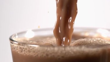 Süper yavaş çekimde temiz kakao temiz bardağa dökülüyor, parlak beyaz arka plan, taze ışıklandırma, narin köpük