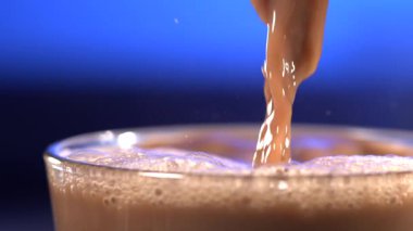 Süper yavaş çekim ipeksi kakao kurdelesi merkez yüzeye vuruyor, yoğun köpük ve hafif dalgalanma, parlak.