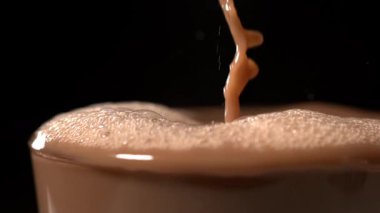 Süper yavaş çekim dinamik kakaolu su damlacıkları, köpük kaplama ve yüksek enerji çarpması, koyu renk.