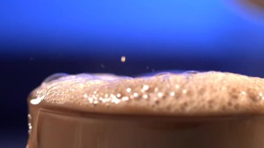 Süper yavaş çekimde bol kakao köpüğü taşar küçük damlacıklar düşer, köpüklü baloncuk dokusu kahverengiye