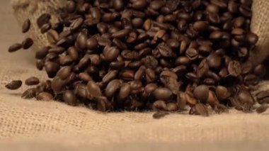 Süper yavaş çekim bol kahve çekirdeklerini çuval bezi üzerine dökme, ağır akış, koyu kahverengi tonlar, hasat titreşimleri, zengin