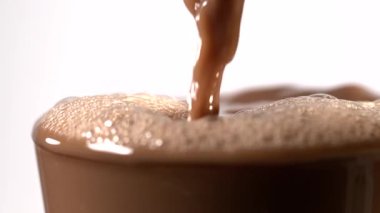 Süper yavaş çekimde havadar kakao taşar, cam kenarından dökülür, yumuşak köpük ve küçük damlacıklar kalkar, parlak