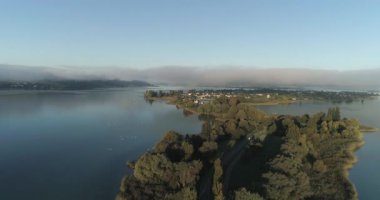 Gün doğumunda Aerial View Gölü Adası, Sakin Suyun üzerinde süzülen Sis, Yoğun Ağaçlı Kıyı Çizgisi
