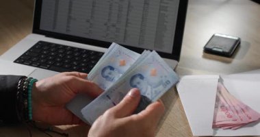 Dizüstü bilgisayardaki Tayland Bahti Çalışma Alanında Hesap Makinesi ve Zarfla, Parmaklarının Detaylı Kapanışı