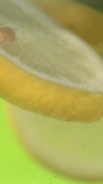 Yeşil suda süzülen Süper Yavaş Hareket Limon Kesme, Kabuk ve Pulun Açılı Kapanışı, Yumuşak Dönüşüm