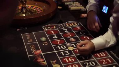 Rulet Masası Satıcısı Renkli Fişler, Loş Işıklandırma ve Odaklanmış Eller Bahisleri Ayarlıyor, Krupiye Kaydırma