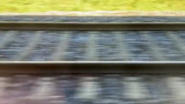 Bir tren kırsal alanda raylar boyunca hızla hareket eder. Dışarıdaki manzara, buradan geçerken yeşil çimenleri ve dağınık ağaçları gösteriyor. Trenin sesi çok net..