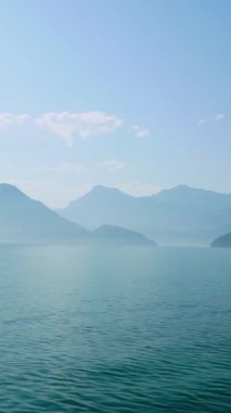 Güneş dağların üzerinden yükselir, aşağıdaki suya ışık saçar. Manzara, berrak bir gökyüzünün altındaki yüksek tepelerle çevrili sakin bir gölü gösteriyor..