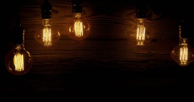 Koyu ahşap bir yüzey üzerinde beş ampul asılı. Ampuller sıcak ışık yayar, boşluğu yumuşak bir parıltıyla doldururlar. Bu sahne akşam saatlerinde rahatlatıcı bir his veriyor..