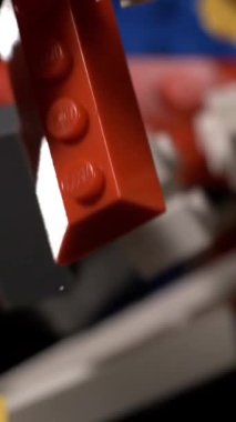 Süper yavaş çekim, Yukarı doğru yavaşça yaklaşan kırmızı ve beyaz tuğlalar Karanlık zemin üzerinde sürükleniyor, parlak çiviler görünür,