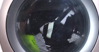 Yavaş çekim, çizgili gömlek, çamaşır makinesinin içinde kıvrılma, siyah beyaz kumaş ve neon çorap manzarası.