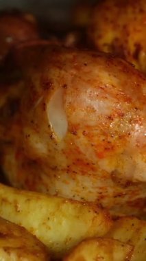 Yakın plan kızarmış tavuklu patates, sıcak fırın altında parlayan altın cilt, görülebilir baharat masajı.