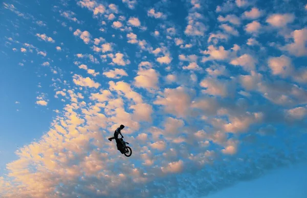 silhouette of a man riding motorbike against sky, extreme sport moto jump