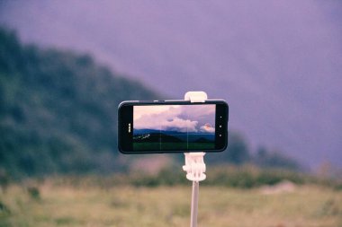 cep telefonu ekranında kaydediliyor, dağlarda yaz manzarası, bulutlu günbatımı gökyüzü 