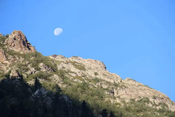 Kayalık dağlar ve aylı mavi gökyüzü 