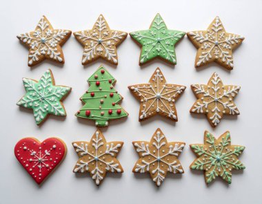 Beyaz arka planda izole edilmiş renkli kremalarla süslenmiş yıldız ve ağaç şekilli bir grup Noel kurabiyesi. Yemek fotoğrafçılığı ve festival içeriği için ideal. 