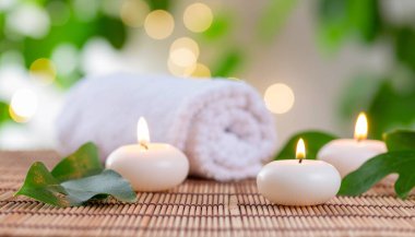 Yanan mumlar, taze yapraklar ve rüya gibi bir arka plan yaratan yumuşak bir ışık ile rahatlatıcı bir spa-esinlenilmiş düzenleme..