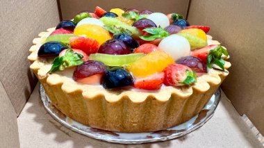 Karton kutuda meyveli tart. Renkli ve lezzetli tatlı seçenekleri. Fırın promosyonları, tatlı menüleri ve tatlıları için mükemmel.