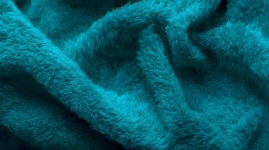 Pofuduk kumaşın yumuşak ve dokulu yüzeyini vurgulayan canlı bir deniz mavisi kumaşının yakın çekim görüntüsü. Ev dekorasyonu veya tekstil geçmişi için mükemmel.