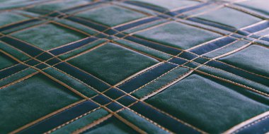 Zengin, yeşil ve donanmadan örülü klasik elmas desenli altın dikişli bir kumaşın yüksek kaliteli makro çekimi. Tekstil geçmişi veya iç tasarım kavramları için ideal.