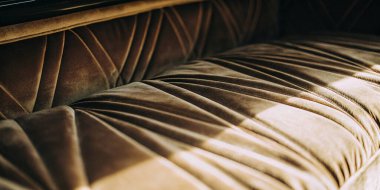 Zarif pliseli ve yumuşak kumaş kıvrımlı lüks kahverengi kadife arabaların detaylı çekimleri. Bu kaliteli iç mekan, yüksek kalitede işçilik ve zengin dokular sergiliyor..